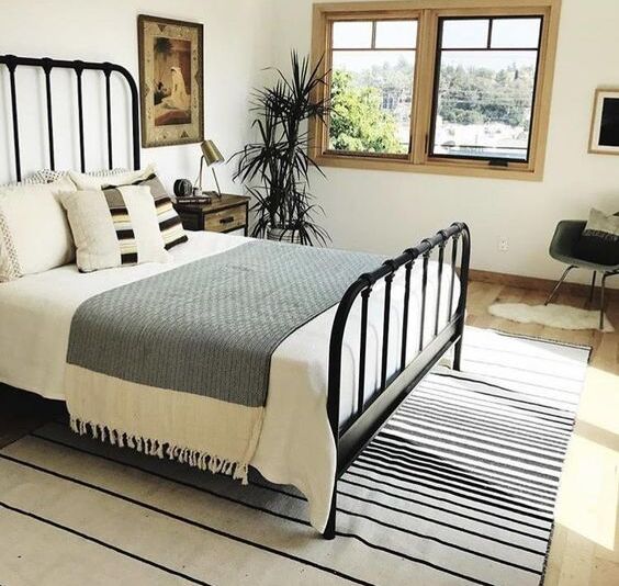 Black Bed Frame Full of Off White Walls And Wooden Flooring