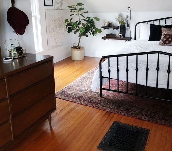 Black Bed Frame with Wooden Flooring and Persian Rug